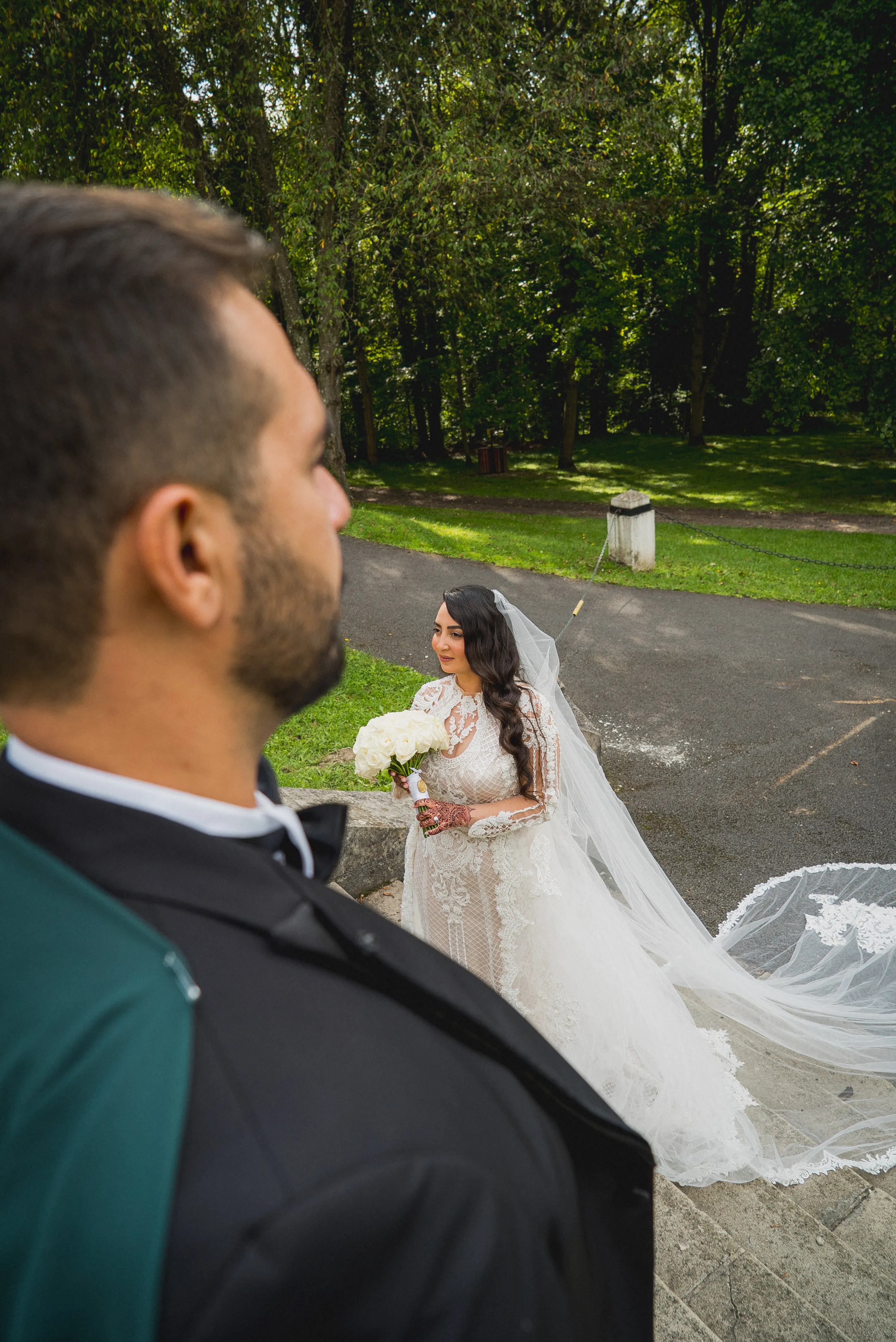 Le marié au premier plan, la mariée en robe blanche derrière lui